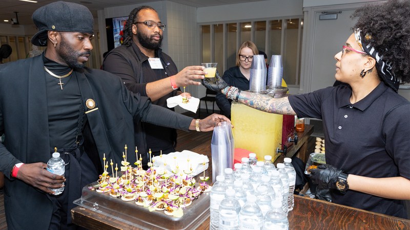 Attendees gather around a table featuring a large, elaborate dessert display during an institutional advancement gathering.