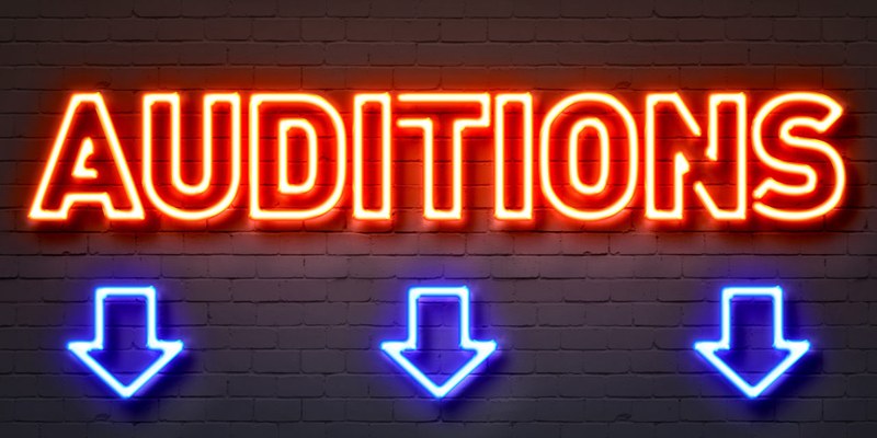 Audition sign in orange neon lights with arrows pointing to look below.