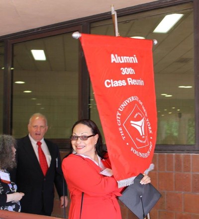 Alum Brunilda Almodovar holding her class banner