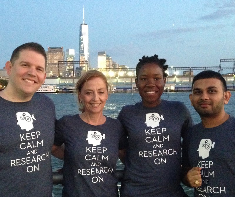 Four researchers stand near water across from the one world trade center
