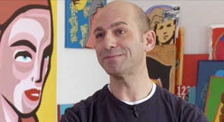 Ryan Seslow sits with several art pieces.
