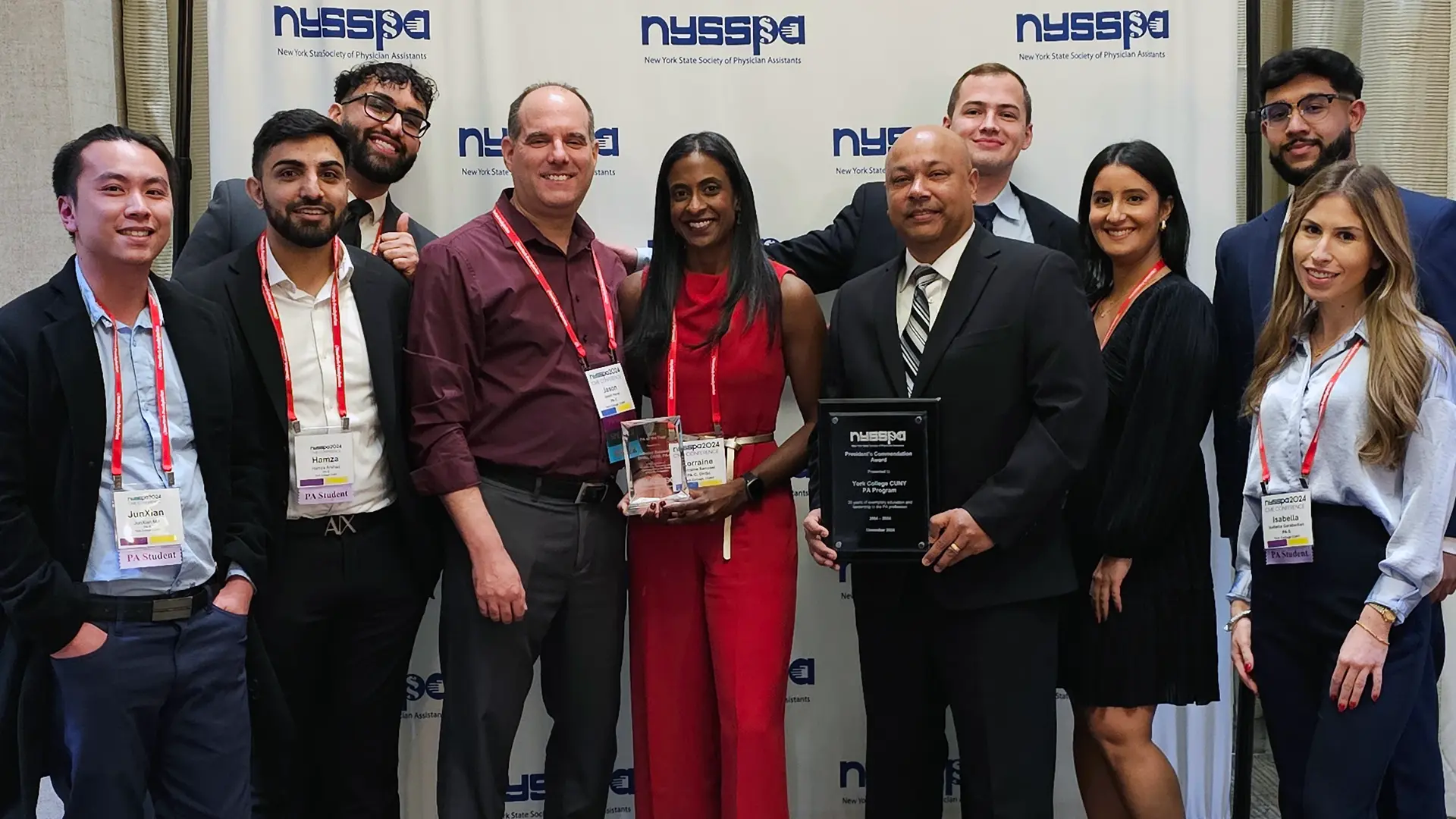 Dr. Lorraine Sanassi, center in red, displays her "Professor of the Year" award surrounded by students and colleagues.